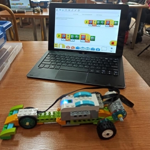 Niewielki pojazd na kołach z klocków lego podłączony do laptopa.