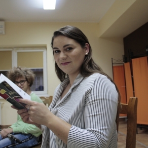 Pani Dyrektor Paulina Frontczak-Pawłowska patrzy uśmiechnięta w obiektyw trzymając w ręku książkę pt. Balladyna".