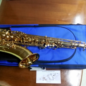 Saksofon położony na niebieskim pokrowcu.