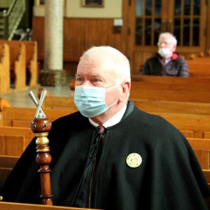 Król Palanta siedzący w kościele, na twarzy ma maseczkę ochronną.