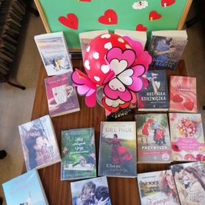 Siedemnaście książek o miłości leży na stole ozdobionym kolorowymi serduszkami.