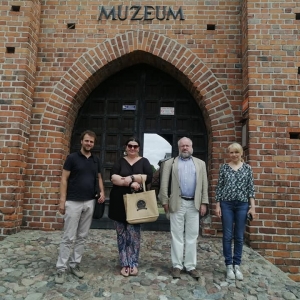 Cztery osoby pozują uśmiechnięte do zdjęcia, przed wejściem do Muzeum w Ręczy. 