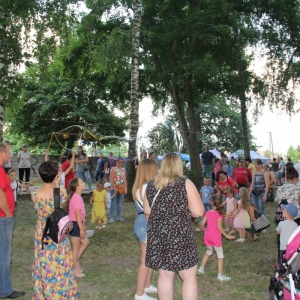 Grupka dzieci bawiąca się dużymi bańkami mydlanymi, a w tle kilkanaście innych osób.