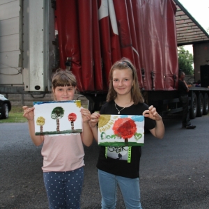 Dwie dziewczynki pokazują namalowane przez siebie prace.