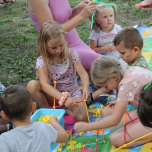 Grupka dzieci bawiąca się na trawniku zabawkami.