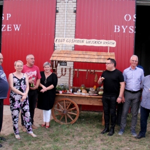 Wójt Gminy Grabów wraz z Kołem Gospodyń Gminy Byszew i organizatorami na tle stoiska z wiejskimi smakołykami.
