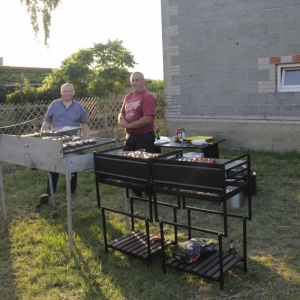 Dwóch panów przygotowuje grilla na pikniku.