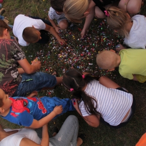 Grupka dzieci zbiera cukierki z rozbitej piniaty.