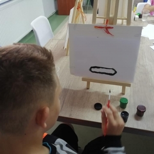 Chłopiec maluje na płótnie.
