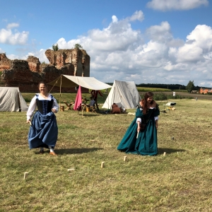 Dwie aktorki na spotkaniu rycerskim uczestniczące podczas zawodów na tle ruin starego zamku.