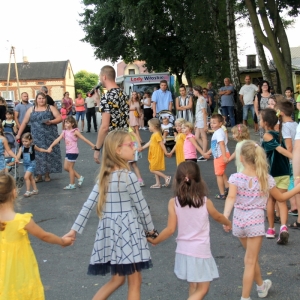 Grupka dzieci i rodziców trzymają się za ręce podczas zabawy na pikniku w Grabowie.