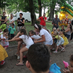Grupka dzieci podczas zabawy zorganizowanych przez animatorkę przeciągają linę.