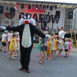 Grupka dzieci bawiąca się przed sceną wraz z animatorem przebranym za postać z bajki.
