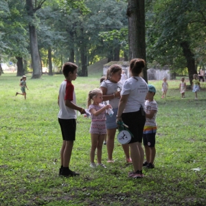 Grupka dzieci z animatorką na trawniku.