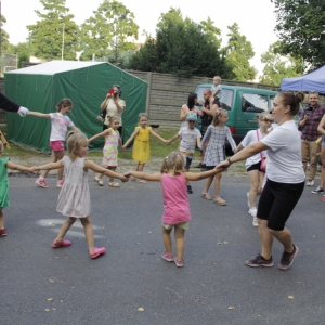 Grupka dzieci podczas tańców i zabawy wraz z animatorką pikniku.