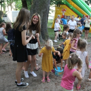 Grupa dzieci podczas zorganizowanej przez animatorkę zabawy podczas pikniku.