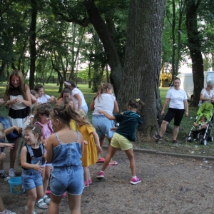 Grupka dzieci podczas zabawy zorganizowanych przez animatorkę podczas pikniku.