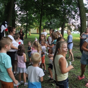 Grupka dzieci podczas zabawy wraz z animatorką podczas pikniku.