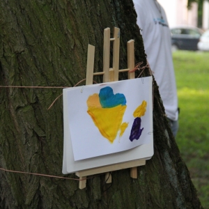 Namalowany przez dziecko obrazek wyeksponowany na drzewie.