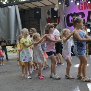 Grupka dzieci podczas tańców i zabawy przed sceną na pikniku.