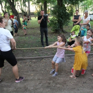 Grupka dzieci podczas zabawy w przeciąganie liny wraz z animatorką.