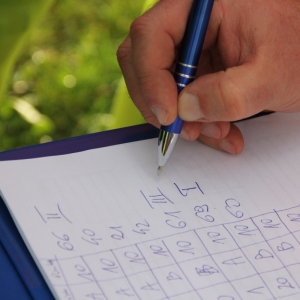 Ręka pisząca coś na notesie z  jakąś tabelką.