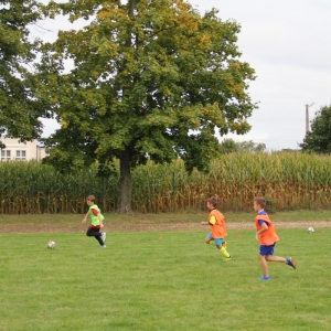 Dzieci w różnych znacznikach grają w piłkę nożną.