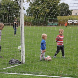 Mali chłopcy bawią się z piłką na boisku.