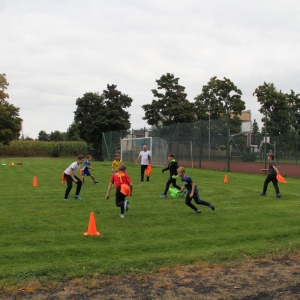 Dzieci trenuję na boisku pod nadzorem trenera.