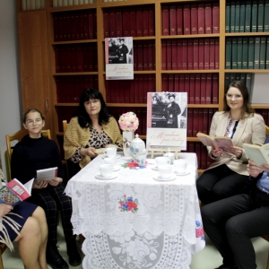Pani Dyrektor Paulina Frontczak-Pawłowska wraz z innymi uczestnikami siedzą przy stoliku z plakatem „Moralności pani Dulskiej" trzymają książki i patrzą w obiektyw.