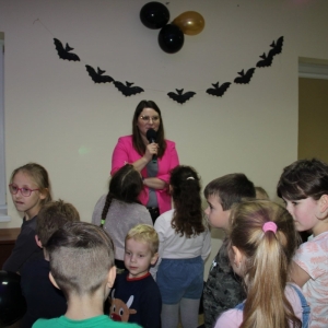 Pani Dyrektor Paulina Frontczak-Pawłowska mówi przez mikrofon  do grupki słuchających ją dzieci. 