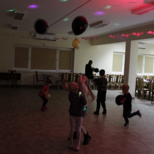 Grupka dzieci tańczących i bawiących się balonikami na sali.
