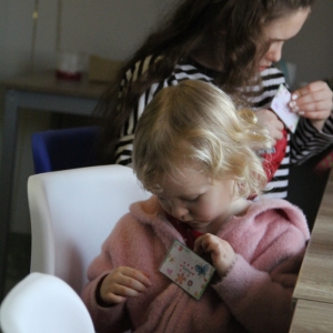 Mała dziewczynka siedzi przy stole i bawi się suwakiem od bluzy.