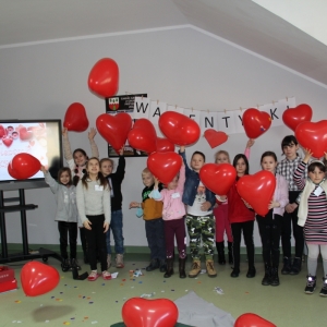 Dzieci rzucają balony w kształcie serca w powietrze.