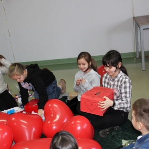 Dzieci siedzą wokół balonów w kształcie serca.
