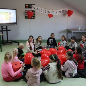Dzieci siedzą wokół balonów w kształcie serca.