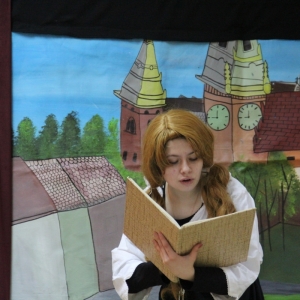 Aktorka udaje postać w spektaklu teatralnym i czyta książkę.