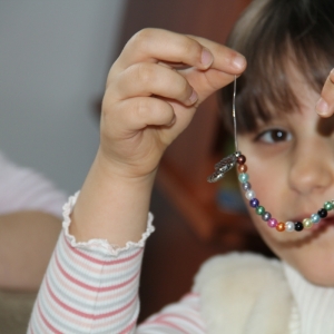 Dziewczynka pokazuje zrobioną przez siebie bransoletkę.