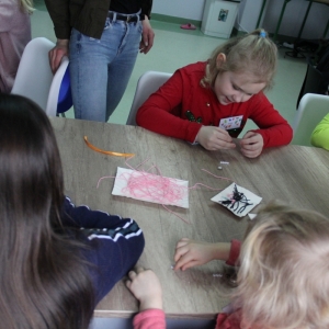 Dzieci robią biżuterie z przyrządów plastycznych.