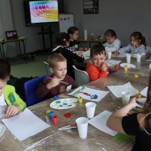 Dzieci malują farbami przy stołach.