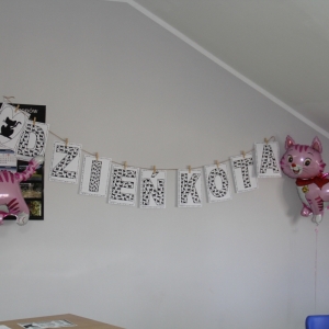 Balony z kotami i napis na ścianie „DZIEŃ KOTA".