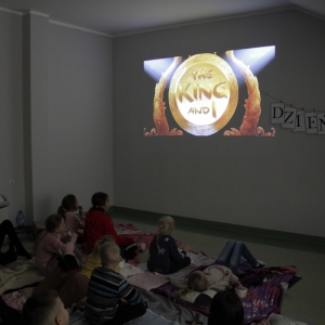Dzieci oglądają film wyświetlany przez projektor.