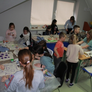 Dzieci bawią się przy stołach malując ozdoby.