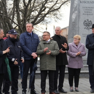 Wójt Gminy Grabów, ksiądz, Senator RP P. Błaszczyk i kilku klaszczących mieszkańców stojących na tle pomnika Tadeusza Kościuszki.
