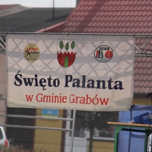 Duża tablica reklamowa z informacją o Święcie Palanta w Gminie Grabów zawieszona na ogrodzeniu.