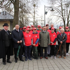 Zdjęcie grupowe drużyny czerwonych gry w Palanta wraz z przedstawicielem zwycięzców ubranego w czarnym stroju w kapeluszu.