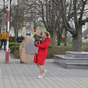 Mieszkanka gminy Grabów z dzieckiem na rękach na tle pomnika Tadeusza Kościuszki.