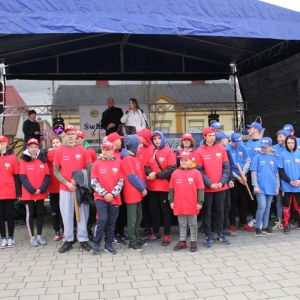 Zdjęcie grupowe drużyny w czerwonych i niebieskich strojach do gry w Palanta na tle sceny, na której stoi Pani Dyrektor GCKB i Wójt Gminy Grabów. 