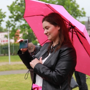Uśmiechnięta Pani Dyrektor GCKB Grabów trzymająca różową parasolkę i telefon.