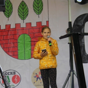 Dziewczynka na scenie z mikrofonem podczas pikniku „Dzień Rodziny".